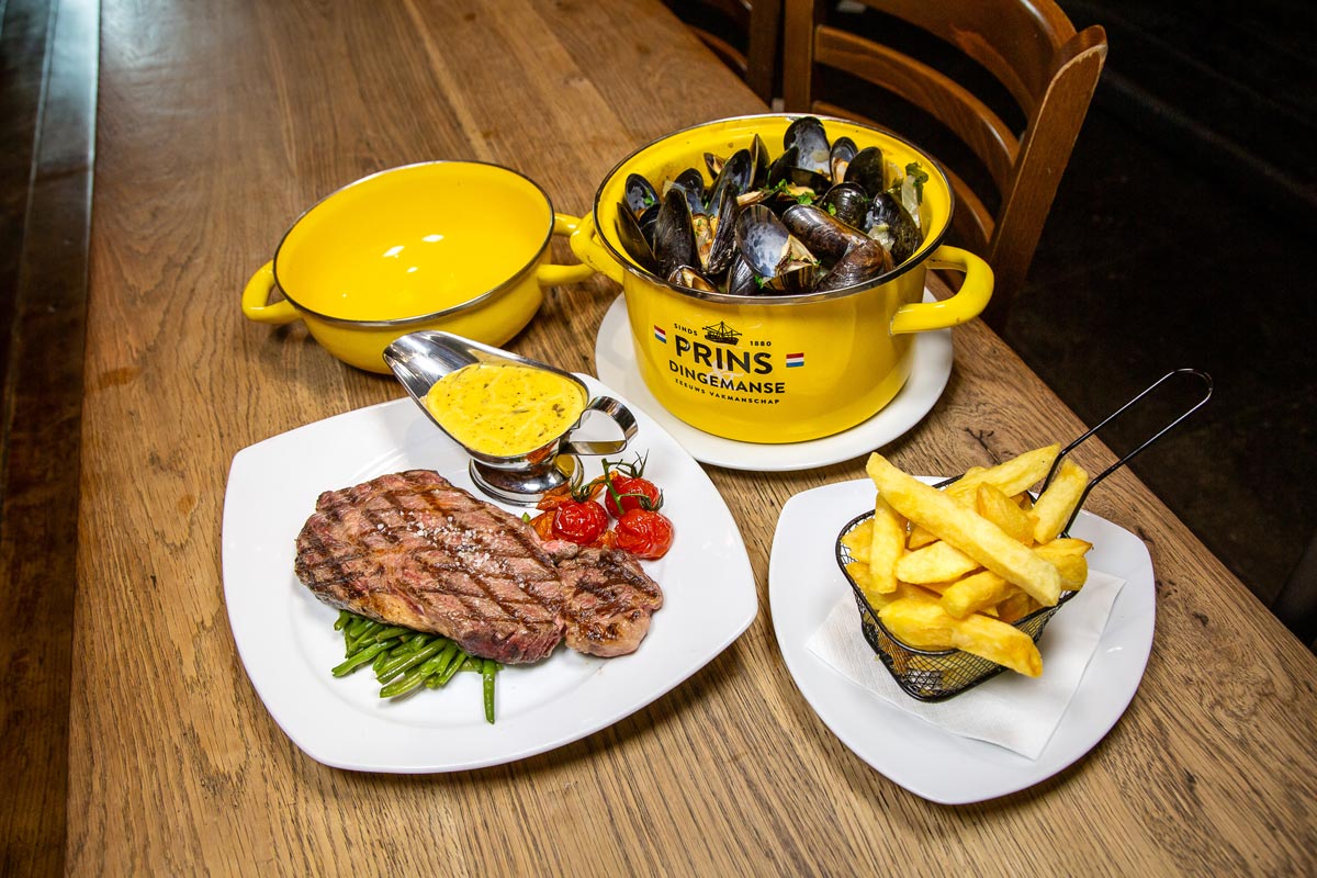 Een entrecôte en mosselen met friet, op een tafel bij Le Roy d'Espagne.